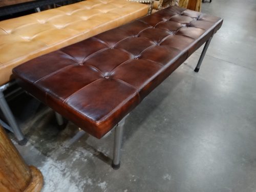 dark brown leather bench with iron legs next to light brown leather top bench with iron legs